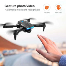 Gray quadcopter drone with front camera and four rotors, near raised hand gesture