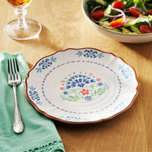 Floral dinner plate with blue and red blossoms, scalloped brown edge.