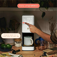 White fully programmable single-serve coffee maker with digital screen and hand pointing