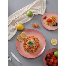 Pink and white dinner plate and bowl with food served on them
