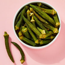 Bowl of green okra chips with sea salt, with a few pieces beside the bowl