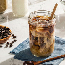 Ball wide-mouth mason jar filled with iced coffee or tea with a wooden stir stick