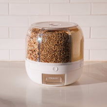White rotating food dispenser with clear lid, filled compartments of dry foods