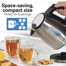 Stainless steel electric kettle with black handle pouring into cup set