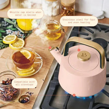 Rose ceramic tea kettle on gas stovetop with blue burner flame