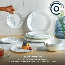 White glass dinner plates and bowl with light blue ribbon vine pattern, stacked on table