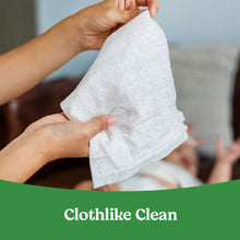 Baby wipes being pulled apart, hands holding a soft white wipe