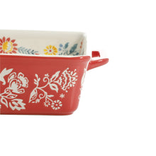 Ceramic baking dish side close-up with white floral scroll pattern on red