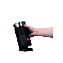 Black electric milk frother held in hand, stainless mixing cup on top