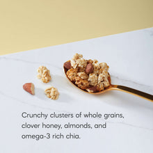 Honey almond granola clusters with almonds in spoon on marble countertop