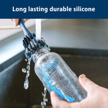Silicone cleaning brush scrubbing a baby bottle inside, water and suds visible