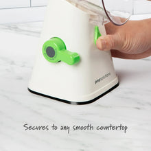 Rotary grater and slicer on countertop, white base and green knob with hand turning handle