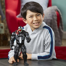 Venom action figure held by a child, black suit with red tongue and white web pattern