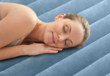 Person resting on a blue airbed mattress with quilted channel pattern