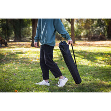 Black quad folding camp chair being carried, folded fabric seat and back