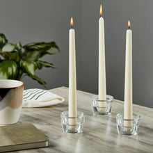 Clear glass taper candleholders with open cups holding three white taper candles