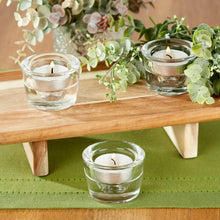 Clear glass candleholder cup holding a tealight candle, open rim and round votive shape