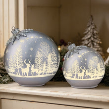 Two silver ornaments with deer silhouettes and woodland pattern