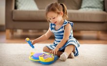Child playing with blue karaoke boombox and purple speaker, using microphone.