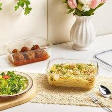 Clear glass storage containers with snap lids filled with prepared foods