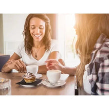 Person holding a white single-serve coffee cup at breakfast table