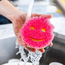 Pink scrub sponge in a hand, with water bubbles and two eye holes and smile