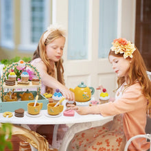 Wooden tea party play set on table with teapot, cups, and cupcake and cookie pieces