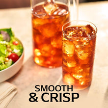 Iced lemon tea in a tall glass with ice cubes and pitcher