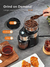 Electric burr coffee grinder with glass bowl of coffee beans and cup nearby