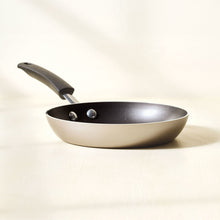 Champagne nonstick frying pan with black handle, two rivets, dark interior