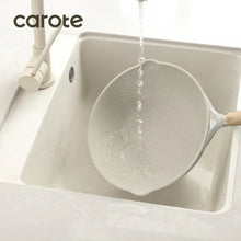 Nonstick frying pan being filled with water, beige speckled nonstick surface, wood-look handle