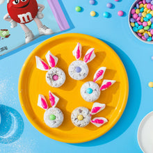Pastel candy-coated milk chocolate eggs on a yellow plate