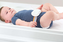 Contoured diaper changing pad with soft buckle strap, baby lying on top