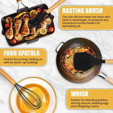 Basting brush, food spatula and whisk with black silicone heads and wood handles on cookware