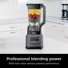 Dark gray blender with clear pitcher filled with diced ingredients and green herbs