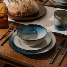 Reactive ceramic dinnerware set place setting with blue-rim bowl and matching plates