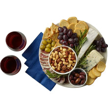 Snack board with crackers, mixed nuts, olives, and cheese plus small nut bowls