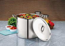 Stainless steel stock pot with lid propped open, filled with vegetables