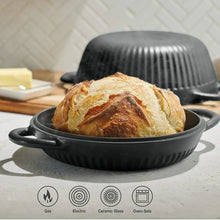 Black enameled Dutch oven holding a round loaf with lid on.
