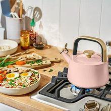 Rose ceramic tea kettle on gas range with flame under base
