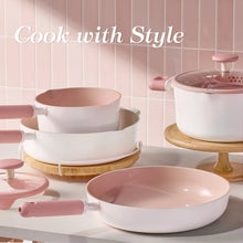Pink-handled ceramic cookware set with two pots and a skillet on countertop