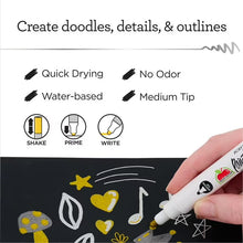 Medium tip paint pen creating metallic doodles and outlines on dark surface