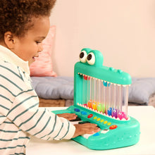 Green crocodile pop piano toy with character drums and child playing at home