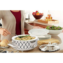 White mini slow cooker with open lid and herbs, serving set on table