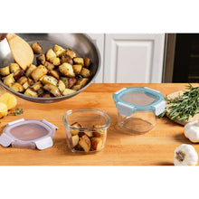 Clear glass food storage container with blue and purple lid, holding food