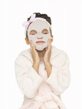 Child wearing a spa face mask and headband while posing near the vanity