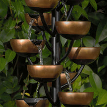 Bronze tiered cups on black frame with curved water arcs