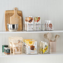 Clear plastic organizer bin on a shelf, holding dry goods containers and jar lids.