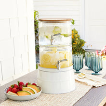 Stacking glass beverage dispenser with acacia wood lid and two spigots, holding yellow drink