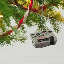 NES console ornament hanging on a tree with ribbon and evergreen branches